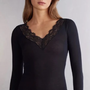 Svart långärmad topp med spetsdetaljer - Elegant svart långärmad topp med v-ringad spetsdetalj vid halsen. Perfekt för en stilren look.