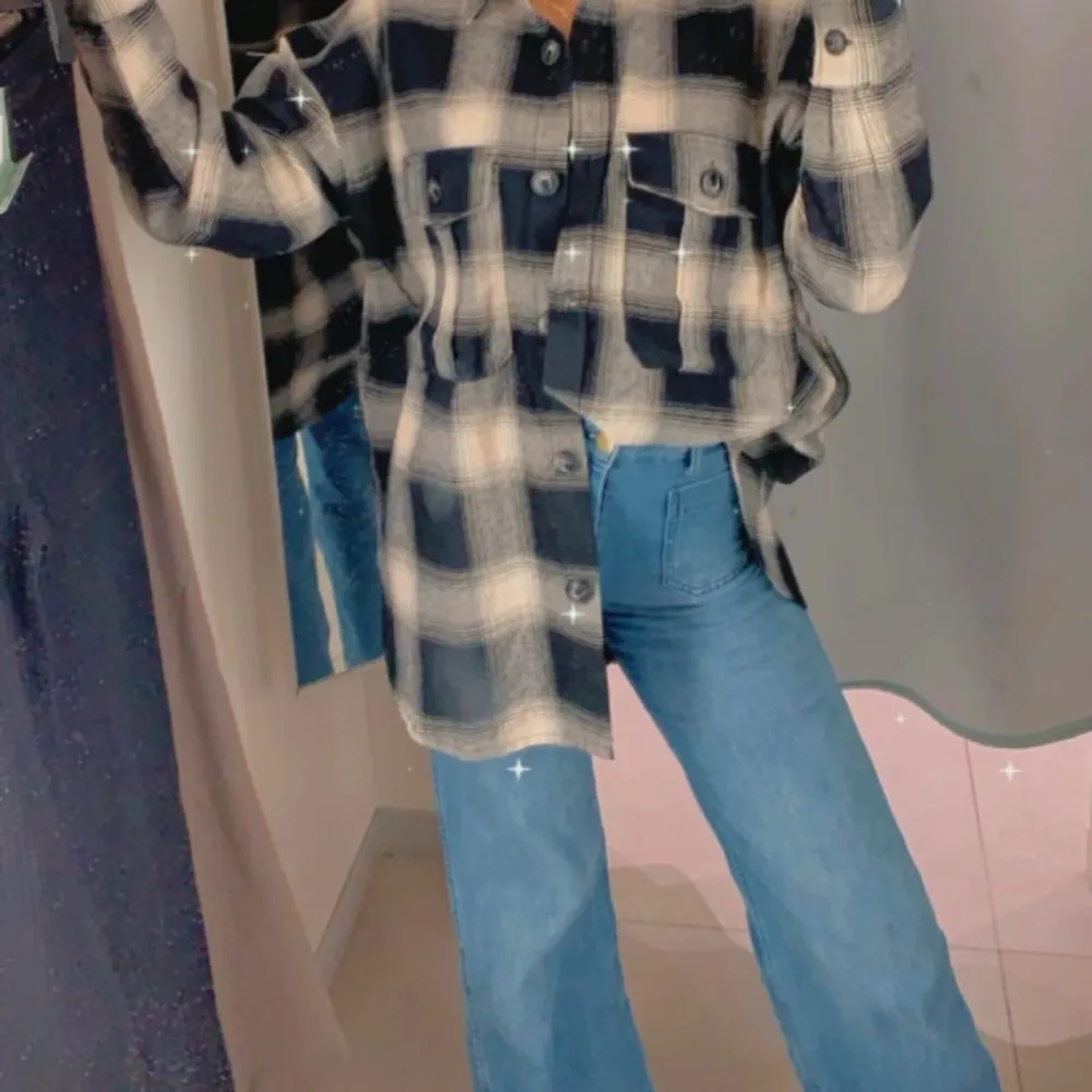 Snygg och trendig rutig overshirt i blått och beige med knappar framtill. Perfekt för lager-på-lager-stil och passar bra till jeans. Den har en avslappnad passform och långa ärmar.. Paidat.