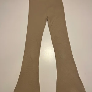 Beige ribbade byxor - Snygga beige ribbade byxor med bootcut-stil. Perfekta för en avslappnad look med en skön passform. De har en elastisk midja för extra komfort.
