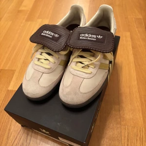 Adidas Wales Bonner sneakers - Snygga Adidas Wales Bonner sneakers i beige och brunt med gula detaljer. Skorna har en unik design med snörning och en stilren siluett. Perfekta för dig som vill ha något annorlunda i garderoben. Använda fåtal gånger och säljs i original förpackning.