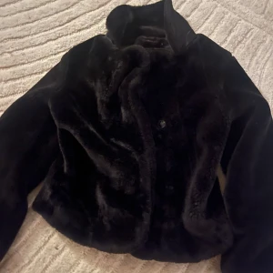 Svart fejk pälsjacka - Snygg svart fejk pälsjacka i storlek M men passar även S. Jackan är mjuk och fluffig. Perfekt för att hålla sig varm under kyliga dagar. Vet inte riktigt vilket märke ai säger  XYZ. Priset kan diskuteras.🤗