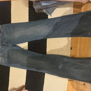 Blå jeans med detaljer - Snygga blå jeans med en klassisk look. De har en straight passform och är dekorerade med små pärlor på bakfickorna för en extra touch. Perfekta för en avslappnad stil.