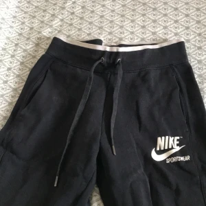 Svarta mjukisbyxor från Nike - Säljer ett par svarta mjukisbyxor från Nike Sportswear. Byxorna har en justerbar dragsko i midjan och praktiska sidofickor. Perfekta för en avslappnad stil.
