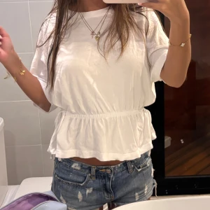 Vit topp från H&M - Säljer en vit topp från H&M med korta ärmar och knytband i midjan för en justerbar passform. Storlek M men passar  XS-M beroende på önskad passform! 