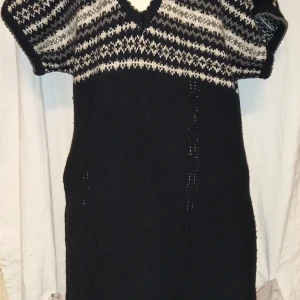 Svart stickad klänning från Fransa - Mysig svart stickad klänning från Fransa med ett mönster i vitt och grått upptill. Klänningen har korta ärmar och en v-ringad hals. Perfekt för kyligare dagar.