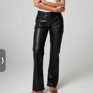 Svarta skinnbyxor - Snygga svarta skinnbyxor med en klassisk straight passform. De har en knapp och dragkedja framtill och är perfekta för en stilren look. Passar bra till både vardag och fest.