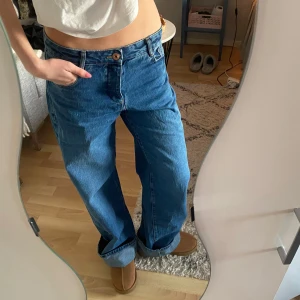 Blå jeans med loose fit - Säljer ett par snygga blå jeans med loose fit och låg midja. De har en klassisk femficksdesign och stängs med knapp och dragkedja. Perfekta för en avslappnad stil. Passar mig som är 177 cm lång men kan vikas upp mer om man är kortare!