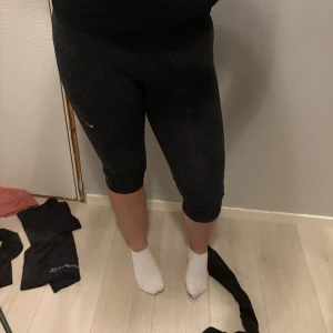 Svarta träningsleggings från Nike - Säljer ett par svarta träningsleggings från Nike med Dri-Fit-teknologi. Perfekta för träning med en tight passform som ger bra stöd. De är knälånga och har en diskret design.