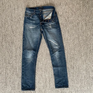 Nudie Jeans - Säljer ett par riktigt snygga och sällsynta Nudie jeans. Jeansen har en riktigt cool tvätt och snygga slitningar. Det är storlek W26/L30 men dom sitter mer som 27-28 i midjan och 30-32 i längd. Jeansen är nästan helt nya och endast använda ett par gånger. Vid minsta fundering är det bara att höra av sig.