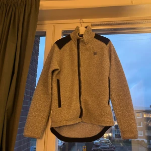 Klättermusen Skoll Zip - M - Varm ulljacka gjord för kalla dagar i en blandning av återvunnen italiensk ull, med aramidförstärkningar.  Perfekt att använda som både jacka eller under ett annat plagg.  Nypris: 4999 kr   Använt men fint skick.