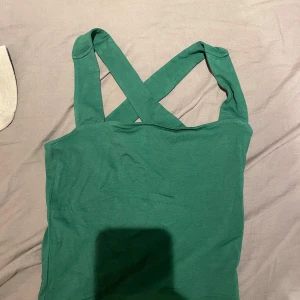 Topp - Mörkgrön topp med korsade band i ryggen, aldrig använd