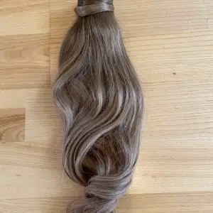 Säljer en lång, vågig hårförlängning i en naturlig ljusbrun nyans från Rapunzel of Sweden, 50 cm. Perfekt för att ge extra volym och längd till ditt hår. Fästes enkelt med clips. Håret är äkta och kan tvättas och stylas. Använt ett fåtal gånger men ligger bara så nu säljer jag. 