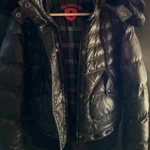 Svart pufferjacka från Wellensteyn - Säljer en snygg svart pufferjacka från Wellensteyn. Jackan har en fluffig huva och är perfekt för kalla vinterdagar. Den är quiltad och har en dragkedja framtill. Supervarm och gosig, den har massa fickor och dragkedja som man kan ta av luvan med🩷 nypris 4327kr den har en liten upprepning på ärmen men de syns knappt