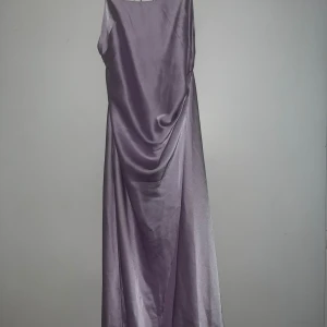 Liliac satin dress med slit - Säljer en satin klänning från Significant Other. Klänningen är i en fin lila färg och har en slit på benet. Säljs för 150kr