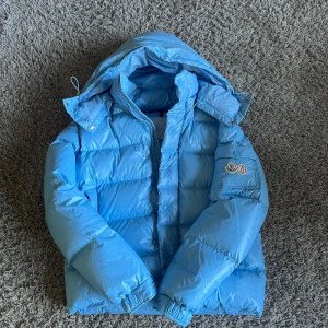 Moncler Maya 70th anniversary - Säljer denna Moncler jacka strlk 2 då jag inte är nöjd, det är en r*p med 2 flaws (kolla bild 4) loggan sitter lite felplacerat och nfc fanns inte med men borde gå att åtgärda hos skräddare (har nfc tagg, kan skicka med) OBS! Skriv innan köp 