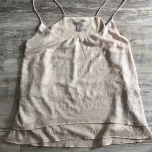 Supersnyggt linne  - Festligt Linne med smala axelband. Beige-guld i färgen med silvriga glitterinslag!