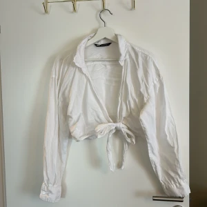 Vit knytblus från Zara - Säljer en superfin vit blus från Zara. Den är långärmad och har en snygg knytning framtill som ger en chic look. Perfekt för både vardag och fest! 💫
