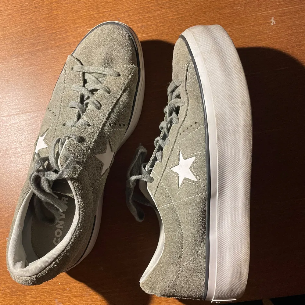 Säljer ett par snygga gröna Converse One Star sneakers i mocka. De har en vit stjärna på sidan och en tjock vit sula. Skorna är i hyfsat skick och perfekta för vardagsbruk. De har snörning och är bekväma att gå i.. Skor.