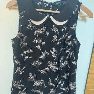 Topp  - Lite lösare modell. Silverfärgade knappar.  Polyester.