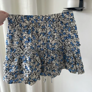 Blommig kjol/skort (kjol med shorts i). - Söt blommig skort (en kjol som har shorts i sig). Mycket skön och smidig eftersom den skyddar om kjolen skulle kunna blåsa upp. Den är i medium men passar även för small.