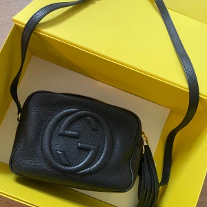 Gucci väska  - Väska från Gucci i svart skinn och frans vid dragkedja. Axelband som går att justera. Kvitto finns. Finns dock ingen kartong, endast dustbag