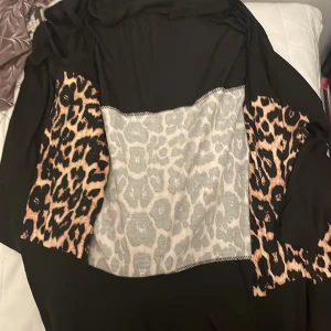 Svart tröja med leopardmönster från Violetta - Säljer en cool svart tröja från Violetta med leopardmönster på ärmarna och en grå panel framtill. Tröjan är perfekt för att sticka ut och har en avslappnad passform. Perfekt för höst och vinter!