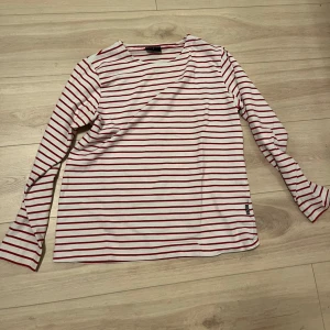Randig långärmad tröja - Säljer en stilren randig tröja med röda och vita ränder. Tröjan har långa ärmar och en bekväm passform. Perfekt för en avslappnad stil.