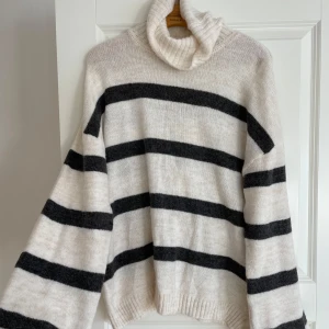 Randig polotröja i svart och vit M oanvänd  - Säljer en mysig randig polotröja i svart och vit. Tröjan har långa ärmar och en bekväm passform med ribbstickade muddar vid ärmslut och nederkant. Perfekt för kyliga dagar!