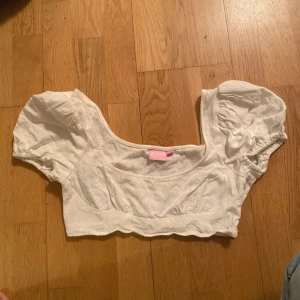Vit croppad linne topp  - Säljer en söt vit croppad topp från Bianca - nelly med puffiga kortärmar och en fyrkantig halsringning. Toppen har elastiska detaljer vid ärmslut och nederkant för en bekväm passform. Perfekt för varma dagar!