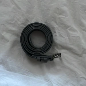 Grått mockabälte med silverfärgat spänne - Snyggt grått mockabälte med ett stilrent silverfärgat spänne. Perfekt för att ge en modern touch till din outfit. Bältet har en slät yta och är enkelt att justera för bästa passform. Skriv för mer info eller bilder.