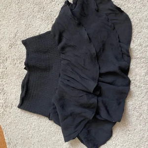 Svart kjol från Shein - Snygg svart kjol från Shein med volangdetaljer och en elastisk midja för en bekväm passform.