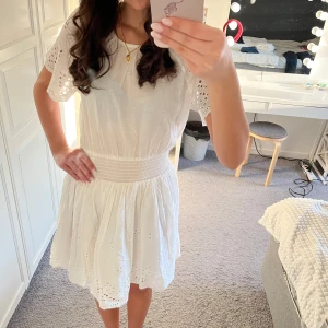 Vit klänning från Amelie & Me - Vit sommarklänning från Amelie & Me i storlek XS. Klänningen har korta ärmar med spetsdetaljer och en elastisk midja. Perfekt för sommaren och är ENDAST använd 1 gång. Nypris 450kr