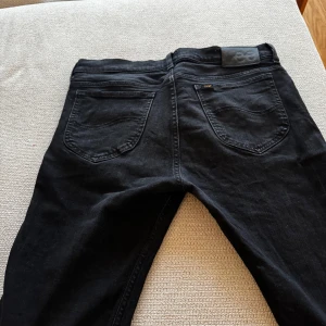 Svarta jeans från Lee - Snygga svarta jeans från Lee i modellen Rider. De har en klassisk femficksdesign med dragkedja och knapp framtill. Perfekta för en stilren look.