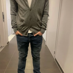 Grå cardigan från Polo Ralph Lauren - Säljer en stilren grå kofta från Polo Ralph Lauren. Koftan har knappar framtill och en klassisk v-ringning. Perfekt för lager-på-lager och passar till många olika outfits. Passar även S