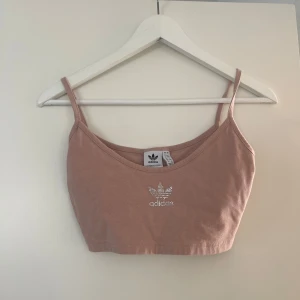 Beige linnetopp från Adidas - Snygg beige/ljus rosa linnetopp från Adidas med smala axelband och en glittrig logga framtill. Endast använd 1 gång så är i nyskick! 