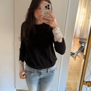 Svart tröja med spetsdetaljer från H&M - Säljer en svart tröja från H&M med vackra vita spetsdetaljer på ärmarna och ryggen. Den är i storlek L men passar i S 