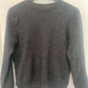 Grå stickad tröja från East West - Säljer en stilren grå stickad tröja från East West. Tröjan har en klassisk rund halsringning och långa ärmar. Perfekt för kyligare dagar och enkel att matcha med olika outfits. Passar både till vardag och mer avslappnade tillfällen. Tröjan är i storlek M men är lite mindre i storlek så den passar bra för dig med storlek S. 