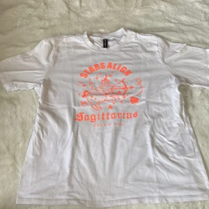 Vit t-shirt med tryck från H&M Divided - Säljer en vit t-shirt från H&M Divided med ett coolt orange tryck av stjärntecknet Skytten och texten 'Stars Align Sagittarius Dream Big'. Perfekt för astrologiälskare!