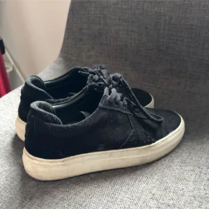 Svarta sneakers från Axel Arigato - Snygga svarta sneakers från Axel Arigato i mocka med vit sula. Skorna har klassisk snörning och en stilren design som passar perfekt till vardagsoutfiten.