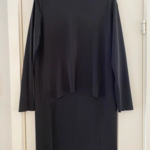 Svart topp från COS - Snygg svart topp från COS i storlek S. Tillverkad i 100% polyester med en stilren design och långa ärmar. Perfekt för en minimalistisk look. Ny svart långärmad topp i strl S från COS.  Tröjan är längre baktill.  Ny, aldrig använd.  Mått Över bröstet: ca 52 cm Längd från axeln och ner framtill: ca 58 cm Längd från axeln och ner baktill: ca 90 cm  100% polyester  Kommer från ett djur och rökfritt hem.