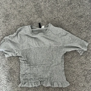 Grå kortärmad topp med volangdetaljer - Snygg grå tröja