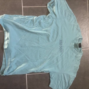 Ljusblå t-shirt från Nike - Säljer en ljusblå t-shirt från Nike med texten 'Just Do It' diskret tryckt på framsidan. T-shirten är kortärmad och tillverkad i ett mjukt material som känns skönt mot huden.