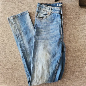 Blå jeansbyxor - Snygga blå jeansbyxor med klassisk femficksdesign. De har en rak passform och är perfekta för en avslappnad stil. Byxorna har en traditionell dragkedja och knapp framtill. Finns en fläck som inte går bort i tvätten. 