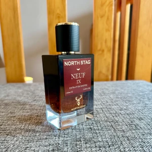 Neuf IX Extrait de Parfum från North Stag - Upptäck Neuf IX, en exklusiv extrait de parfum från North Stag. Flaskan rymmer 100 ml och har en elegant design med en mörk tonad glasflaska och svart kork. Doften bjuder på rika noter av vanilj, amber, labdanum, benzoin och tonka, vilket ger en varm och inbjudande upplevelse. Endast testad. Förpackning saknas.