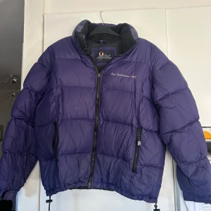 Vintage lila dunjacka från Peak Performance 365 - Säljer en snygg vintage lila dunjacka från Peak Performance. Jackan har en dragkedja framtill och är perfekt för kyligare väder. Den är långärmad och har en broderad logga på bröstet. Perfekt för dig som vill hålla stilen i vinter! 💜