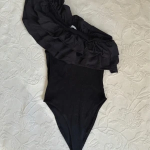 Svart body med volang - Snygg svart body med en axel och volangdetaljer. 💘