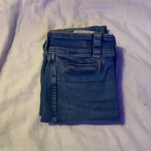 Blå jeans med fickdetaljer storlek 158 - Snygga blå jeans med klassisk design och fickor både fram och bak. De har en knapp och dragkedja framtill samt hällor för bälte. Perfekta för en avslappnad stil.