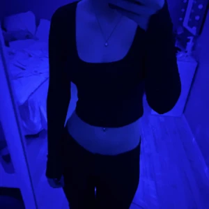 Svart långärmad croppad topp - Säljer en stilren svart långärmad croppad topp med rund halsringning. Perfekt för en trendig look. Passar bra till både jeans och kjol.