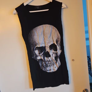 Svart ärmlös topp med dödskalletryck - Cool svart ärmlös topp med ett stort dödskalletryck på framsidan. Perfekt för en edgy look.