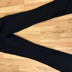 Svarta lågmmidjade mjukisbyxor från Nelly  - Snygga svarta mjukisbyxor med bootcut-stil och knytband i midjan. St xxs. Råka köpa 2 st i samma färg och storlek och glömde bort att lämna tillbaka i tid så nu Försöker jag sälja dem istället!
